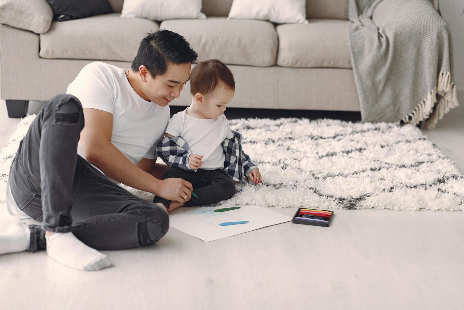 Parent sitting on the floor with a baby, drawing together in a calm home environment