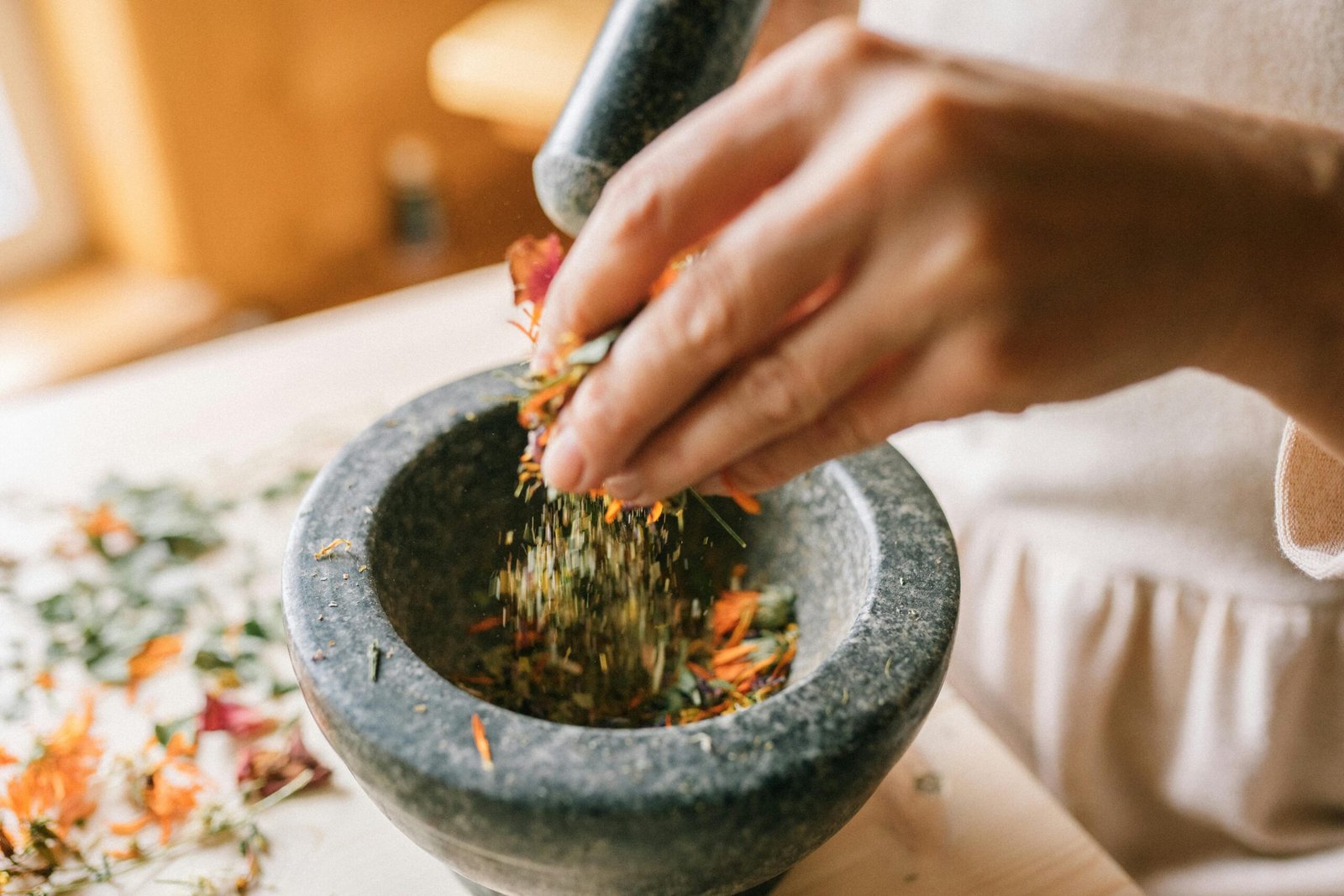 Hands grinding fresh herbs in a mortar and pestle, representing a natural and mindful lifestyle